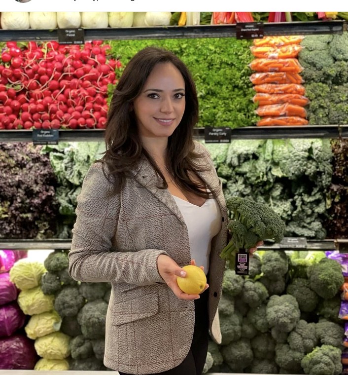 Nazila Nikravesh, MS, RDN in a grocery store holding fresh produce